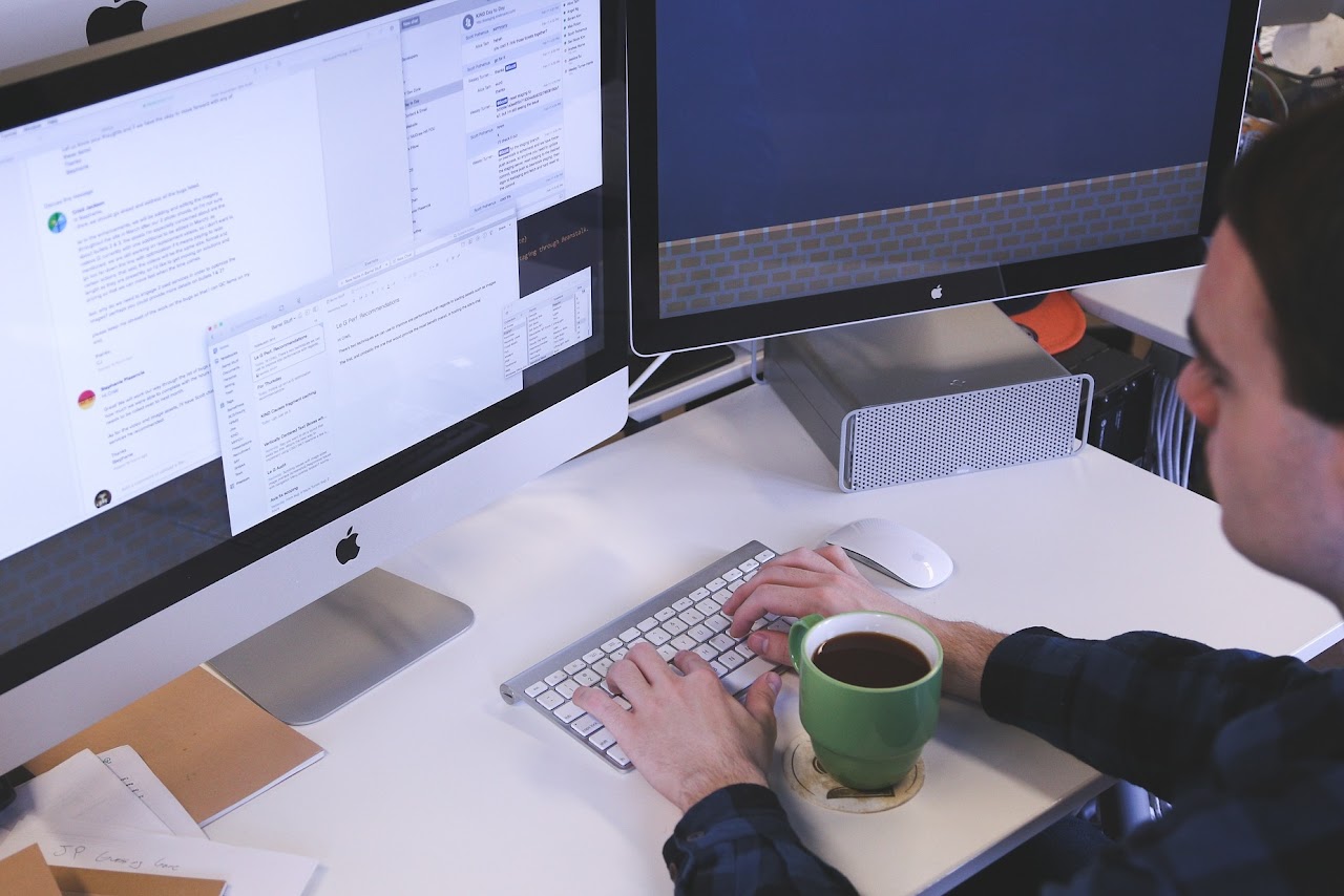 A person sitting and writing on their keyboard in front of a computer